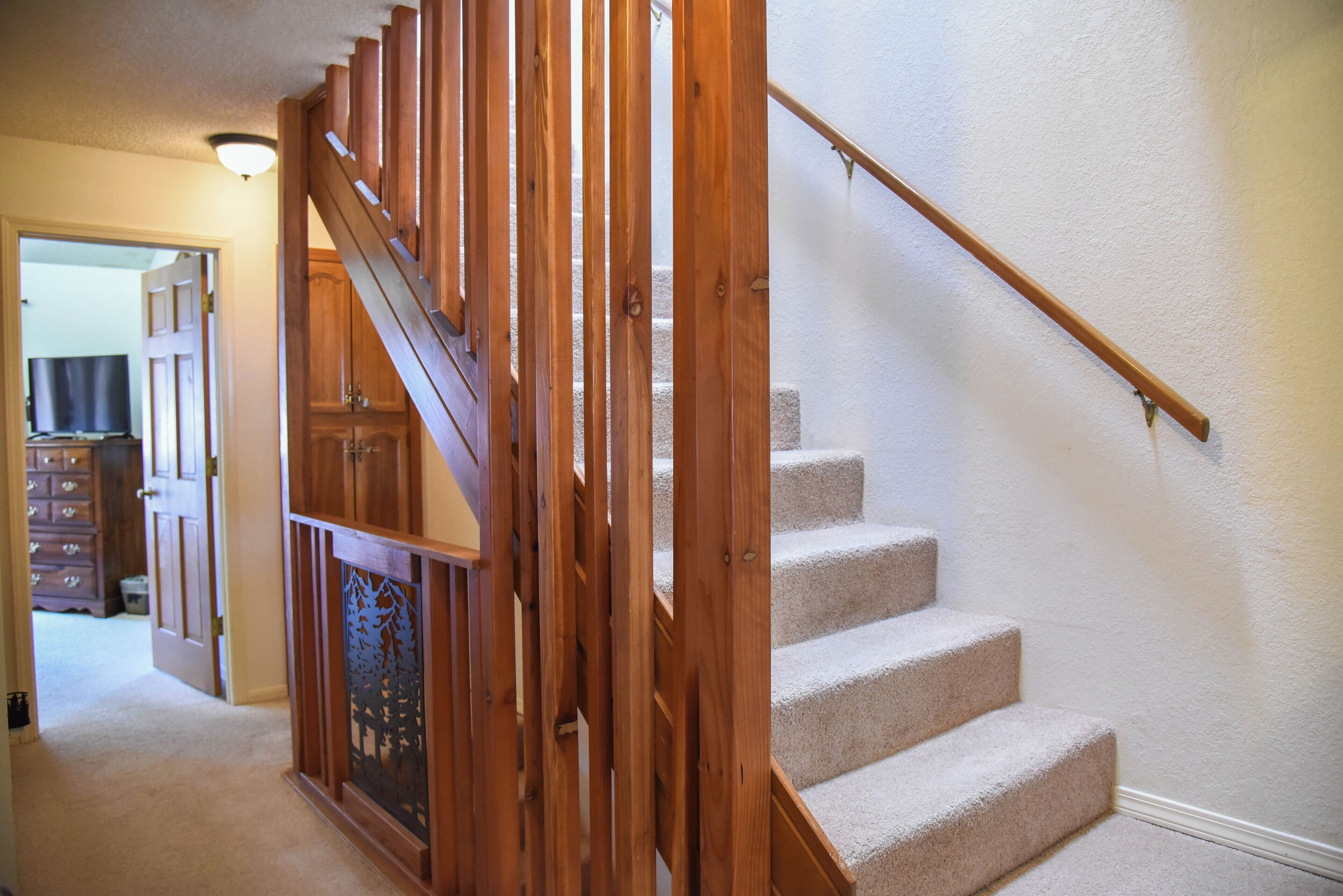 A wooden staircase with beige carpeted steps and a handrail.