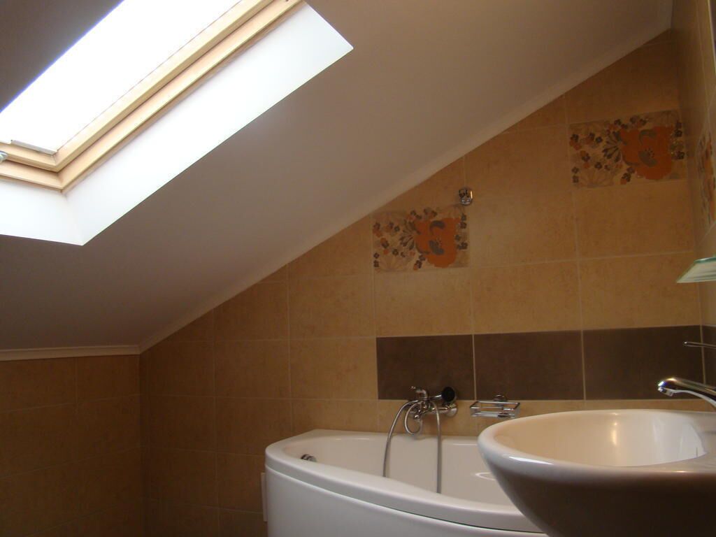 Un baño con tragaluz, bañera y lavamanos.