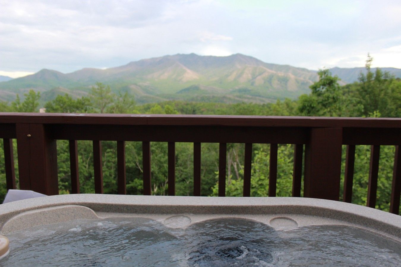 A hot tub on a wooden deck with a view of mountains.