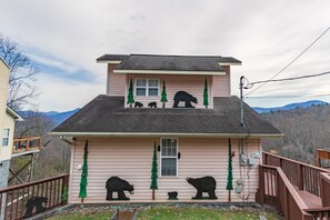 Une maison à deux étages, ornée d’une décoration en forme d’ours sur le toit et d’une statue d’ours sur le porche.