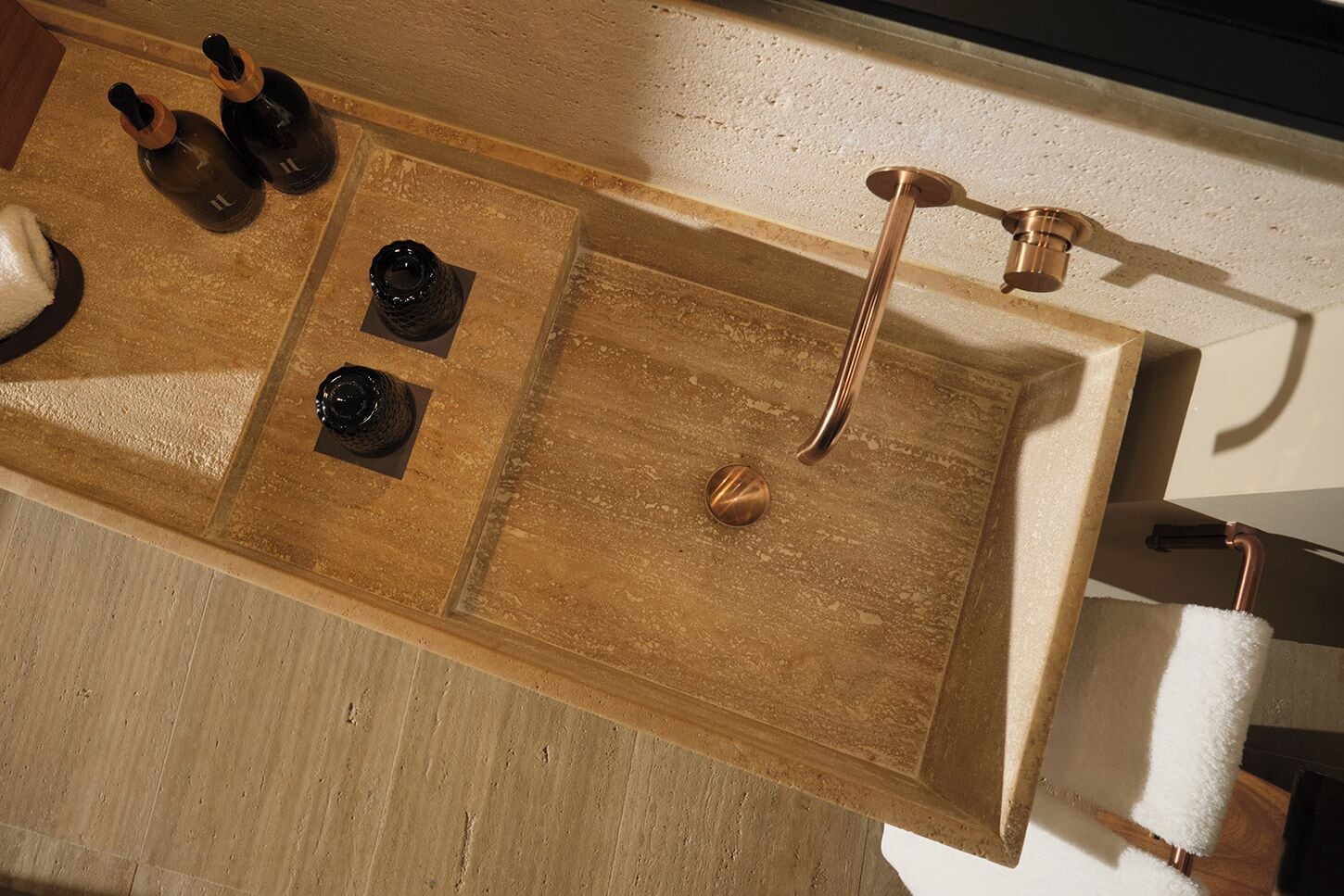 Ein hölzerner Waschtisch mit einem Becken, zwei Flaschen und einem Handtuch.