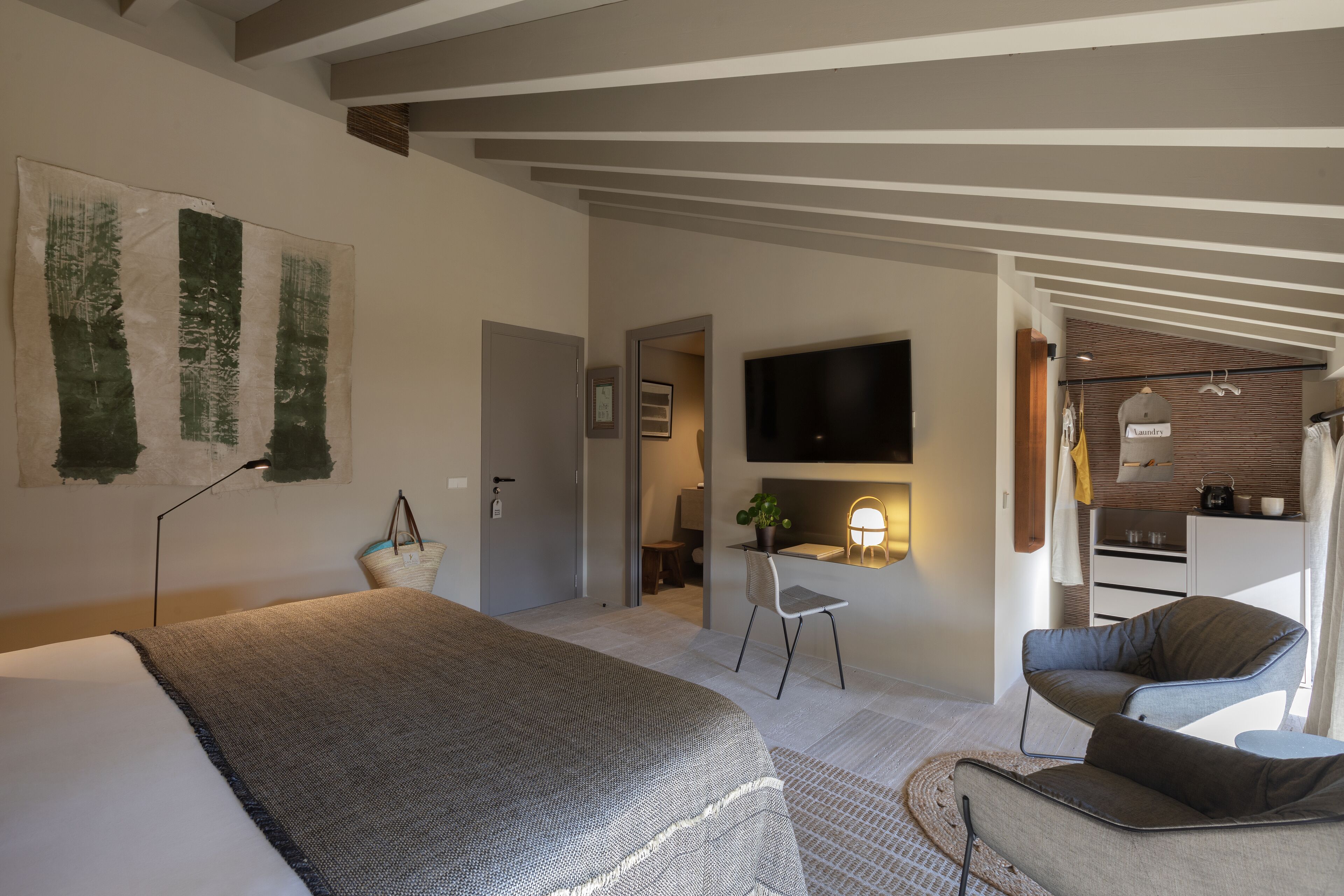 Een moderne hotelkamer met een groot bed, een bureau, een flatscreen televisie en een zithoek met een stoel en een bank.