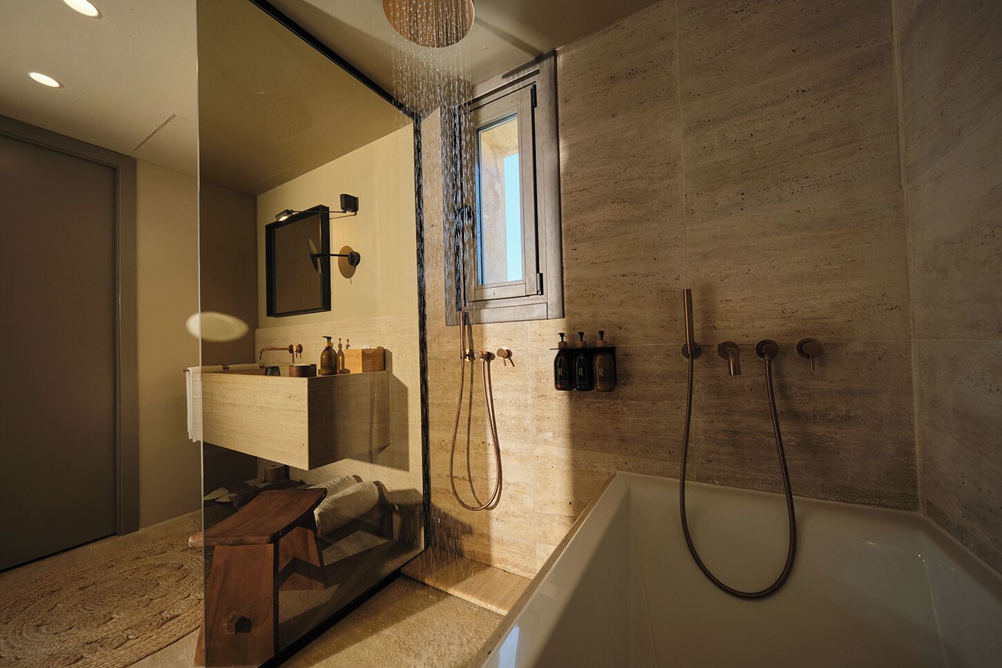 Un baño moderno con una bañera independiente, ducha con mampara de vidrio y tocador con espejo y espacio de almacenamiento.