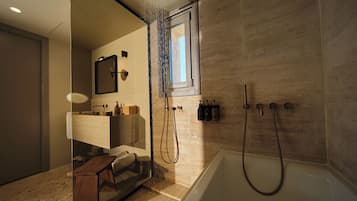 Un baño moderno con una bañera independiente, ducha con mampara de vidrio y tocador con espejo y espacio de almacenamiento.