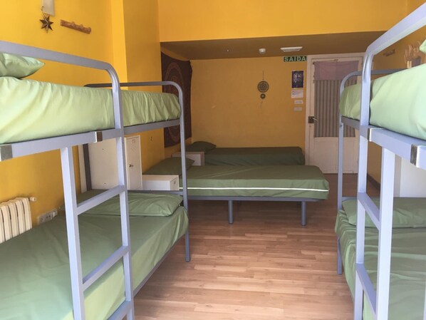A dormitory room with bunk beds, wooden flooring, and a door labeled "SAIDA". - Albergue Azabache - Hostel (Santiago de Compostela)