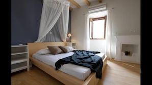 Een slaapkamer met een bed, nachtkastjes, een bedlampje, een raam en een open haard.