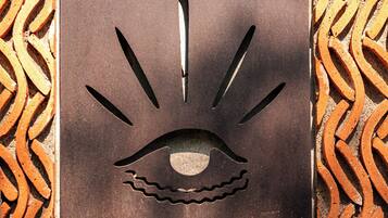 A metal plaque with a stylized eye design and the text "CASA LÚ" on a patterned surface.