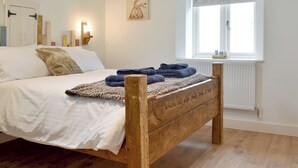 Un lit en bois orné d’une inscription, une fenêtre donnant sur un paysage et un mur décoré d’un tableau.