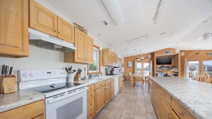 Une cuisine spacieuse avec des meubles en bois, une cuisinière blanche et un grand îlot central doté d’un plan de travail en marbre.