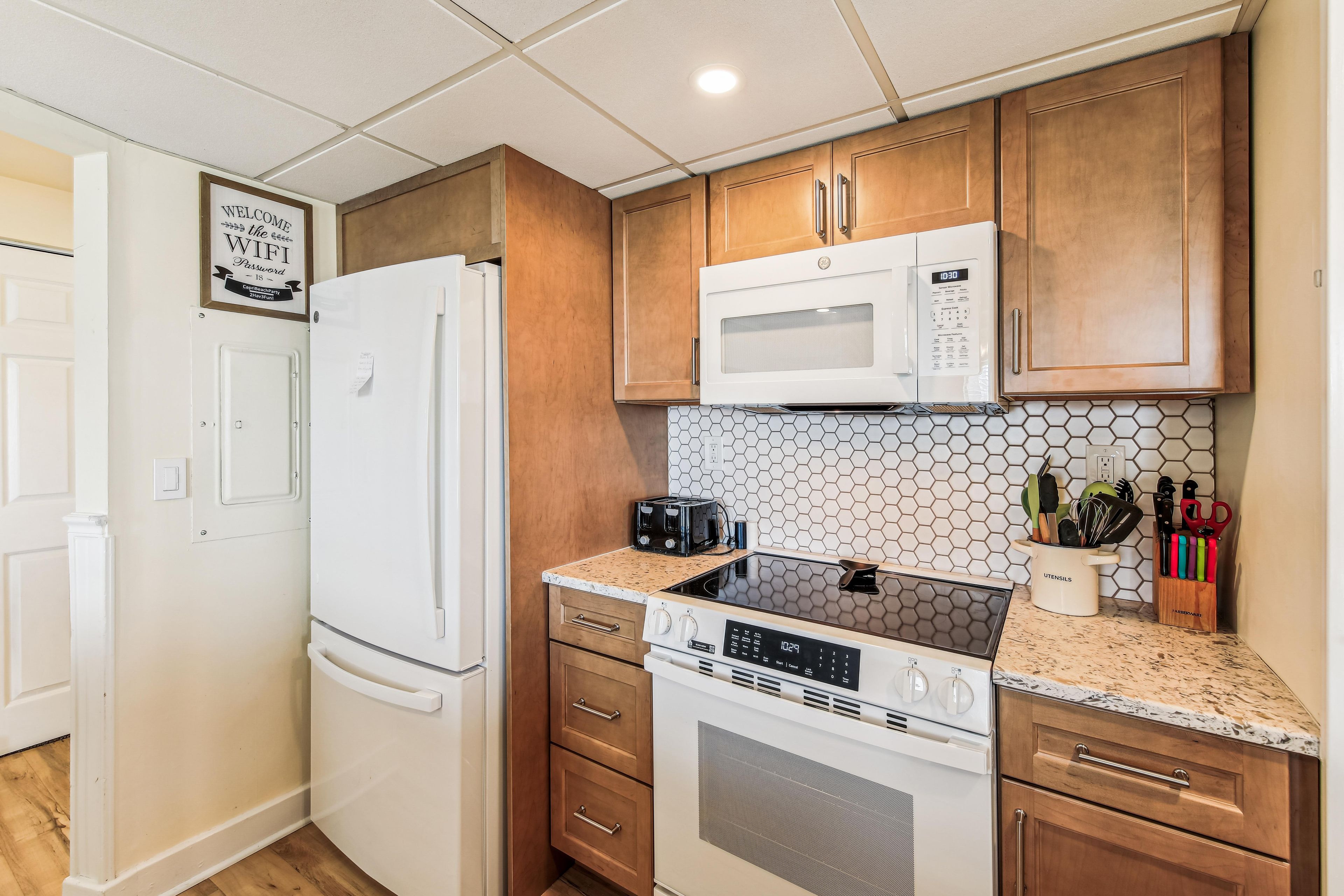 A modern kitchen with wooden cabinets, a white refrigerator, a microwave, a stove, and a dishwasher.