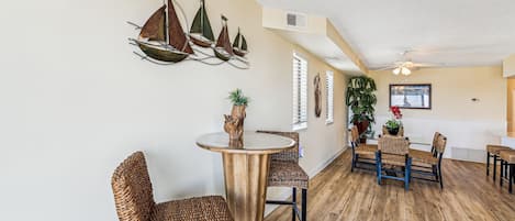 Un comedor con sillas de mimbre, una mesa redonda y una decoración náutica de un velero.
