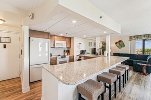 A modern kitchen with a central island, bar stools, and a view to the living area. - XPLORIE ACTIVITIES & LINENS INCLUDED*! 3BR/2BA Capri. Spectacular Bay View! (Ocean City)