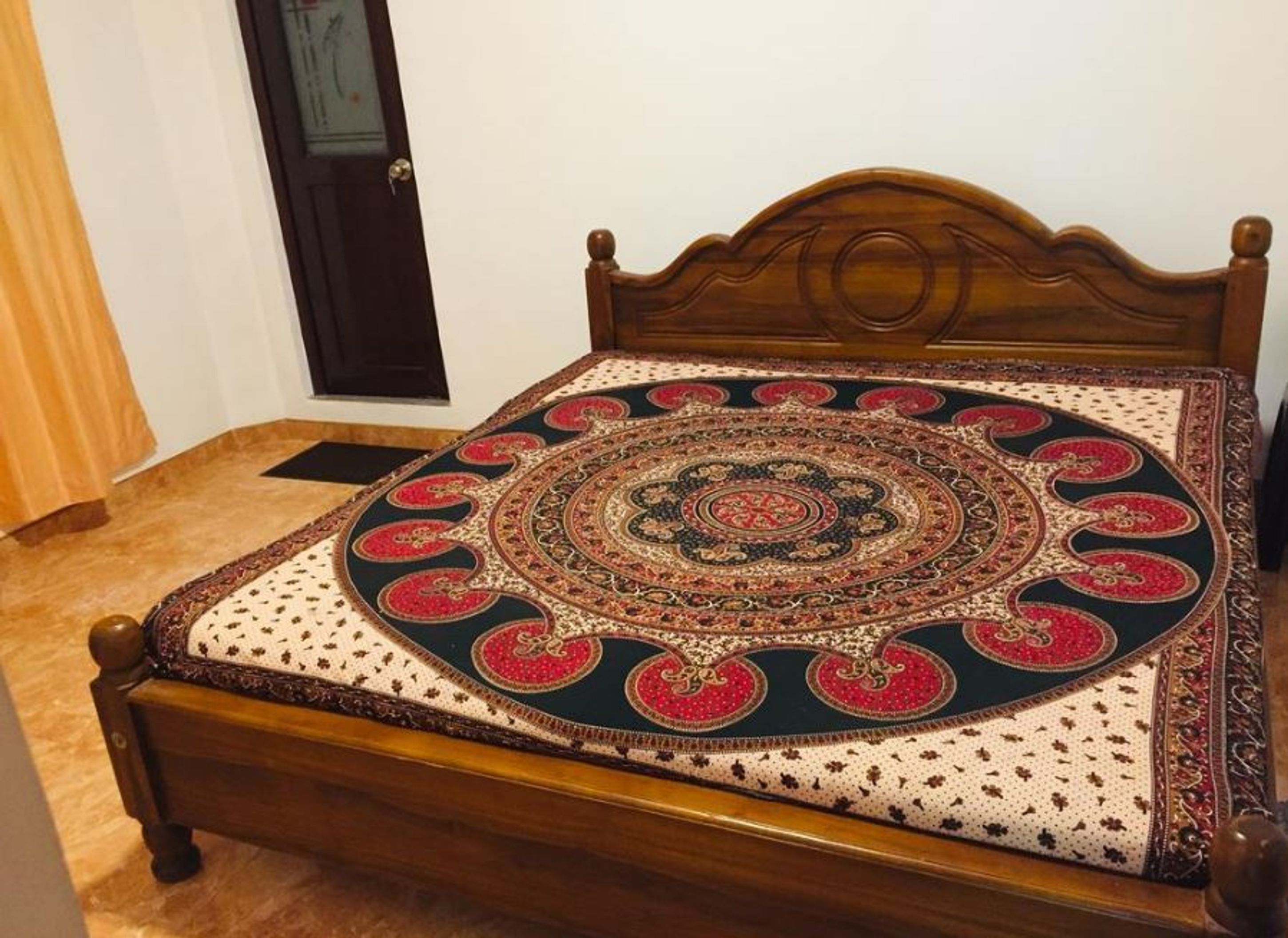 A bed with a patterned bedspread and a wooden headboard.