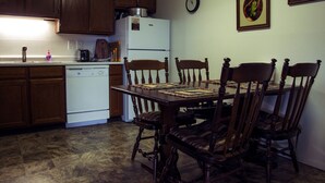 A kitchen with wooden cabinets, a white refrigerator, a dining table with chairs, and a clock on the wall. - Red Dog Retreat Condo - all the comforts of home in Yellowstone paradise (West Yellowstone)
