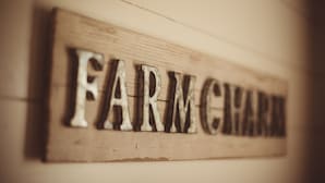 Un letrero de madera con las palabras 'FARM CHART' en letras metálicas en relieve.
