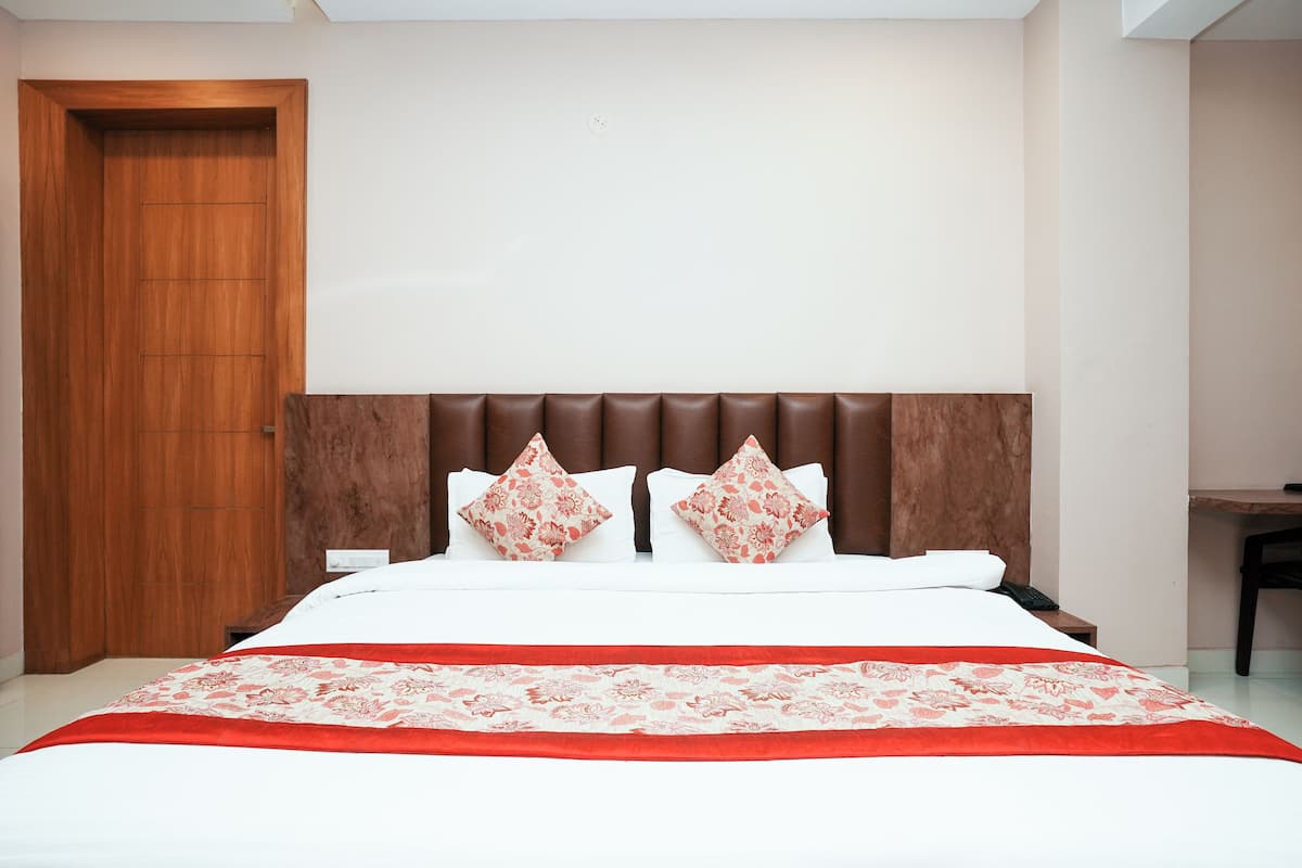 A neatly made bed with a red and white floral bedspread, two matching pillows, and a wooden headboard.