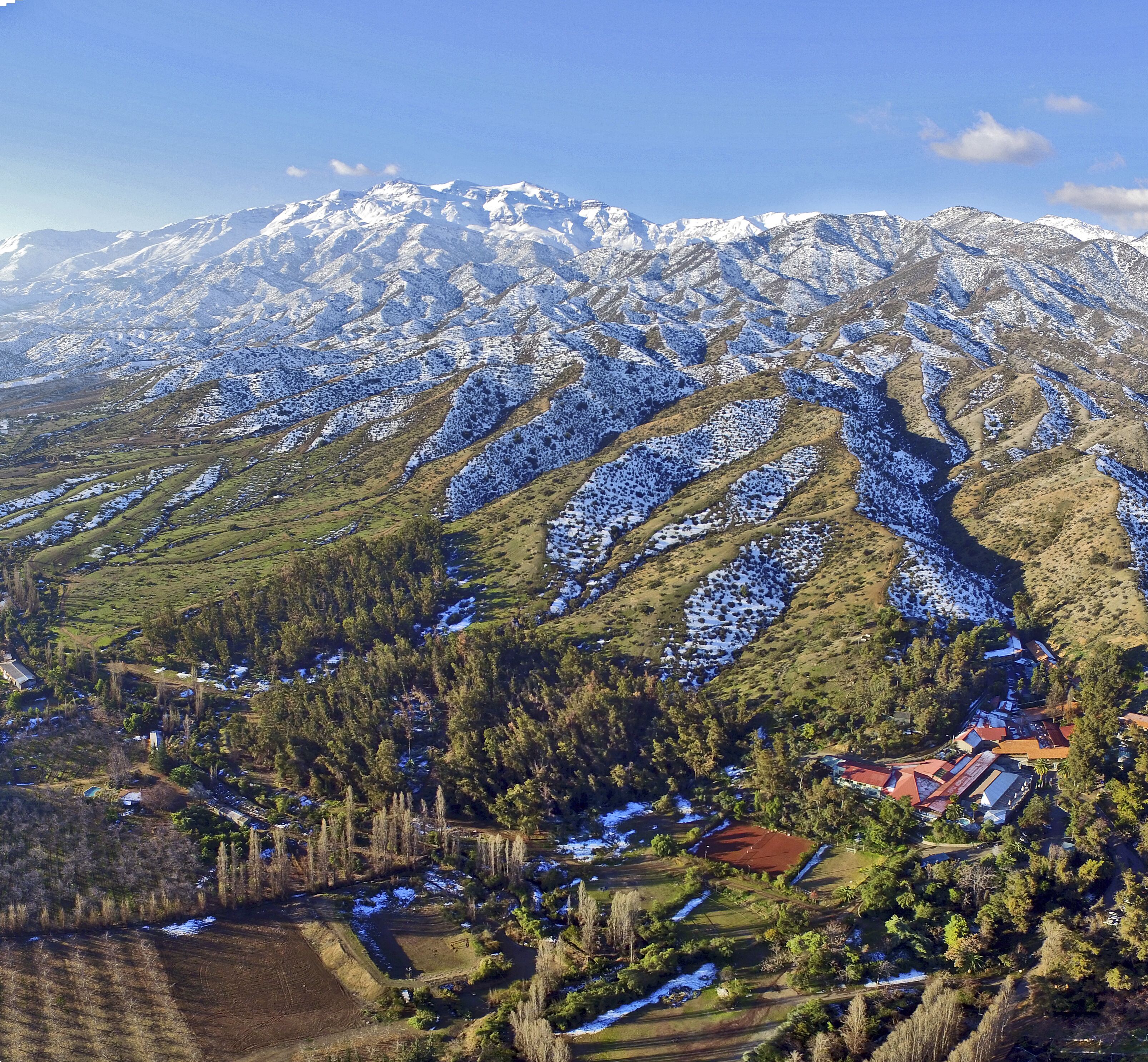 A mountainous landscape with snow-covered peaks and a valley with a small settlement.