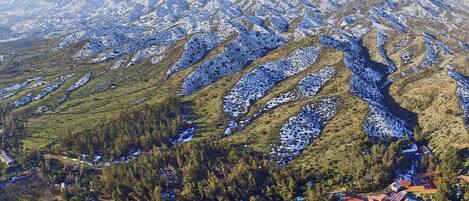 A mountainous landscape with snow-covered peaks and a valley with a small settlement.