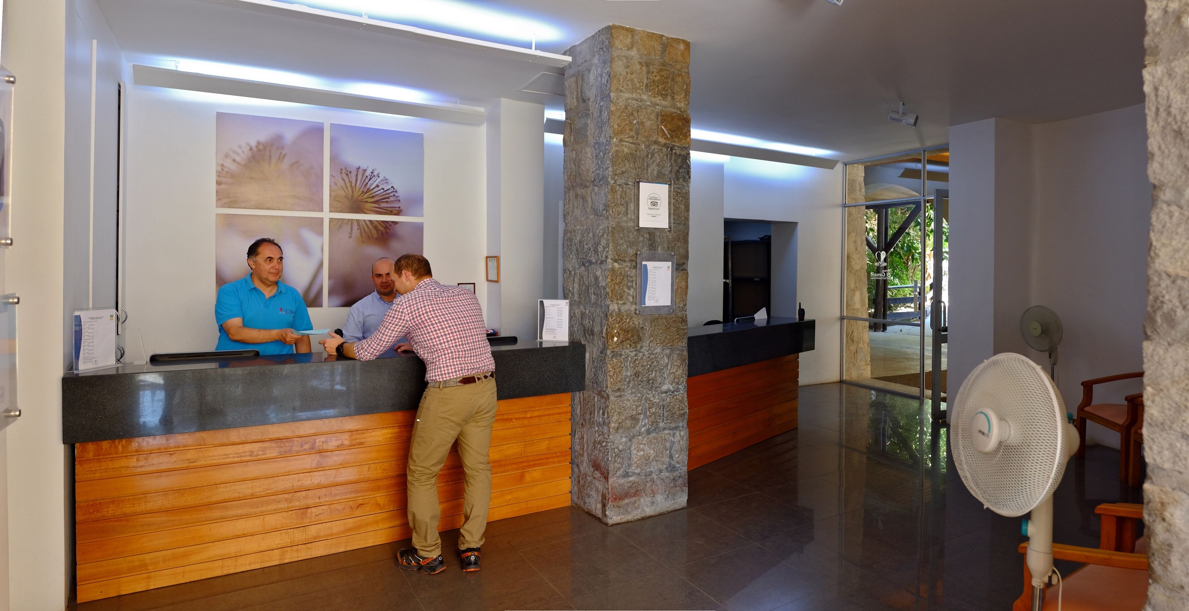 A reception area with a wooden counter, stone pillar, and a fan.
