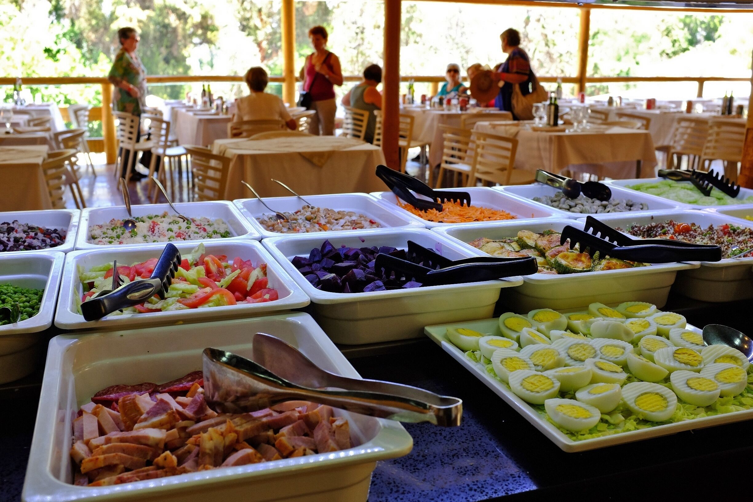 Een buffet met diverse keuzes, zoals vlees, salades en eieren.