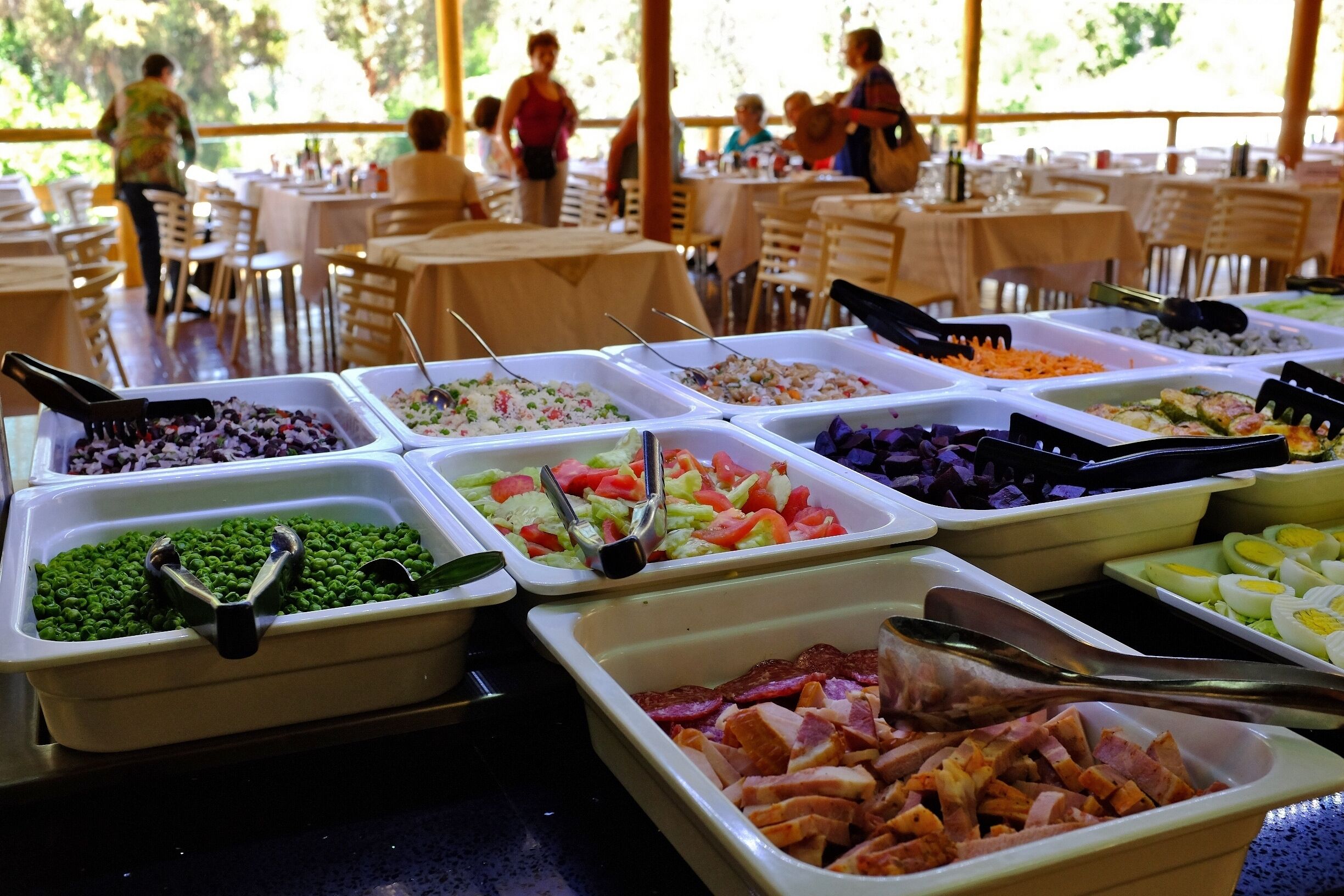 Ein Buffet mit verschiedenen Speisen, darunter Salate, Fleisch und Gemüse.