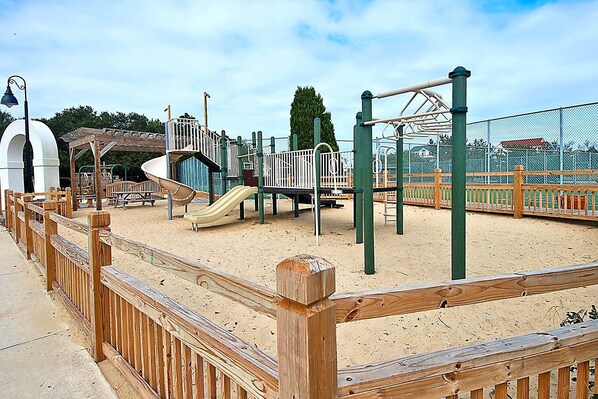 A playground with a slide, climbing structures, and a fenced area.