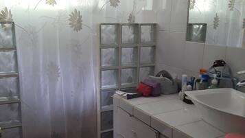 A bathroom with a toilet, a sink, a mirror, and a shower area with a curtain.