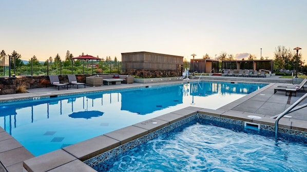 A rectangular pool with a tiled edge, surrounded by lounge chairs and a covered seating area.