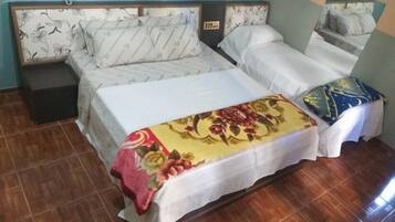 A double bed with a floral bedspread, a nightstand, and a bedside table.