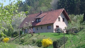 Ein Haus mit geneigtem Dach, mehreren Fenstern und einem gepflegten Rasen.