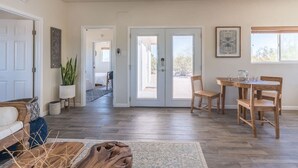 Uma sala ampla com piso de madeira, uma mesa de jantar com cadeiras, um sofá e uma porta que dá para uma varanda.