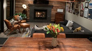 A modern living room with a fireplace, wooden wall, and a dining area with a wooden table and chairs. - Beautiful and Spacious home only 5 minute drive to Canyons Resort---Sleeps 10 (Park City)
