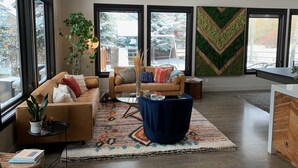 A modern living room with a brown leather sofa, a blue ottoman, and a patterned rug. - Beautiful and Spacious home only 5 minute drive to Canyons Resort---Sleeps 10 (Park City)