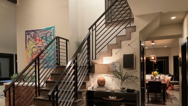 A modern staircase with a metal railing, a colorful abstract painting on the wall, a desk with a lamp, and a dining area in the background. - Beautiful and Spacious home only 5 minute drive to Canyons Resort---Sleeps 10 (Park City)