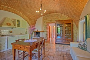 Una cocina amplia con zona de comedor, chimenea y techo de ladrillo tradicional.
