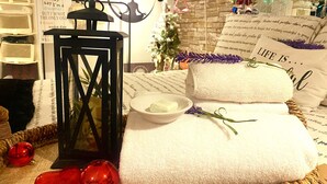 A cozy room with a woven basket, a white towel, a bowl of bath salts, and decorative red ornaments.