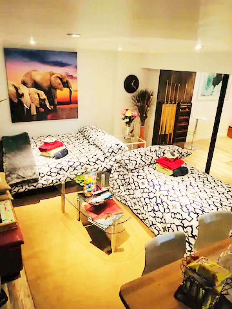 Una sala de estar con un sofá estampado, una mesita de centro y un reloj de pared.