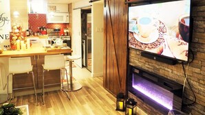 A modern kitchen with a dining area, a fireplace, and a TV mounted on the wall.