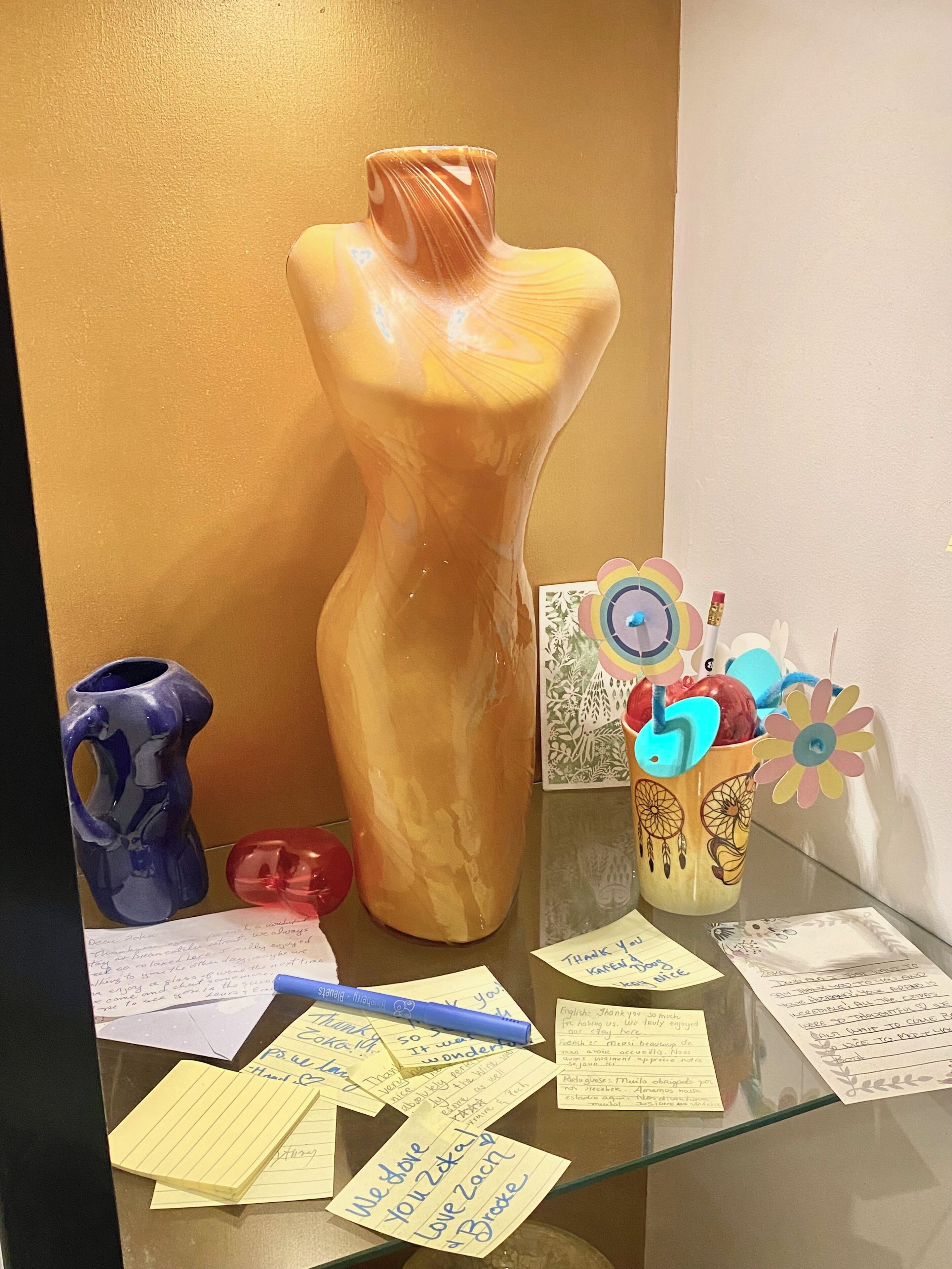 A glass display case with a sculpture, a vase, and various notes.