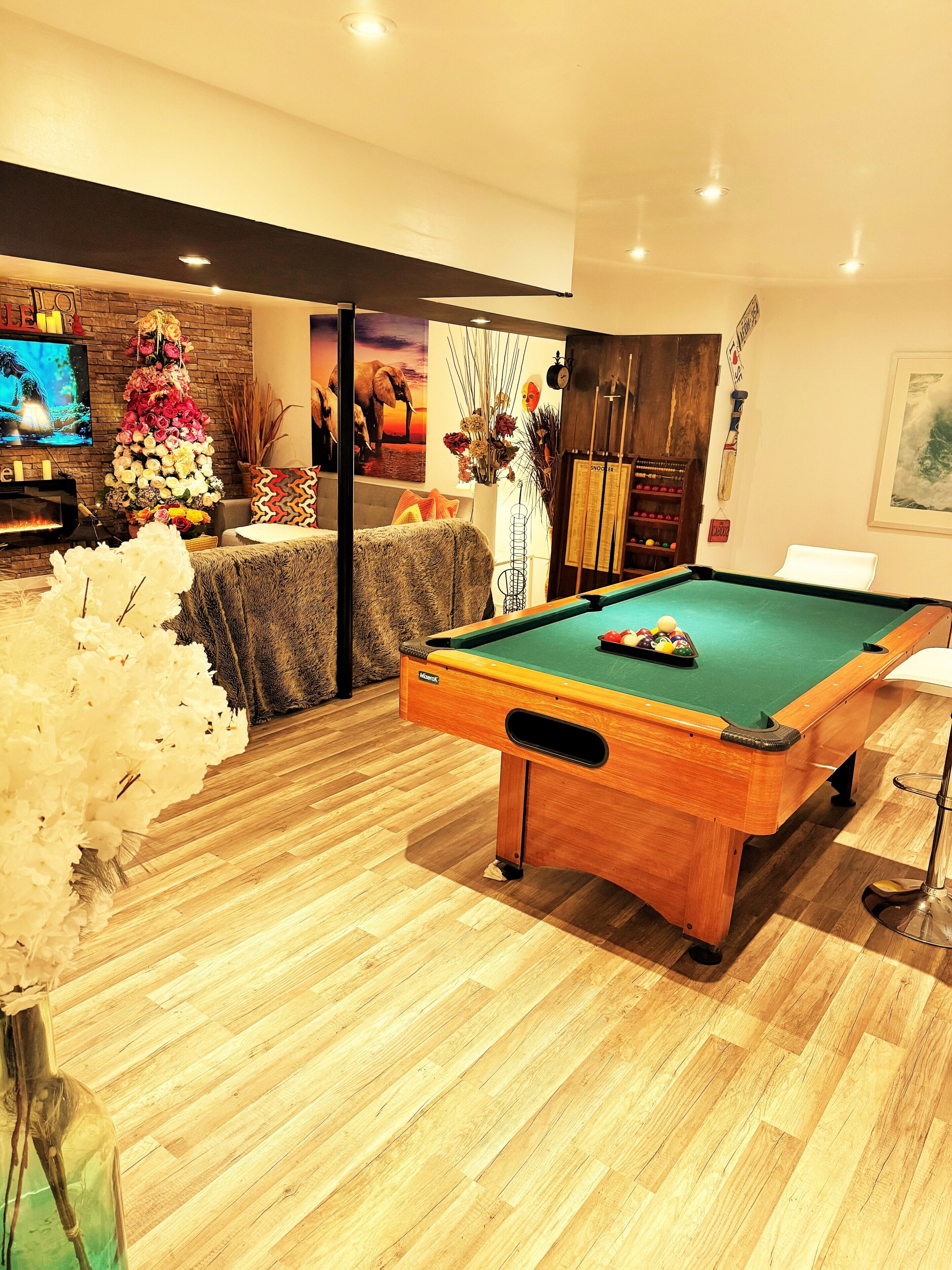 Une table de billard dans une pièce dotée d’un plancher en bois, d’une télévision et d’une cheminée.