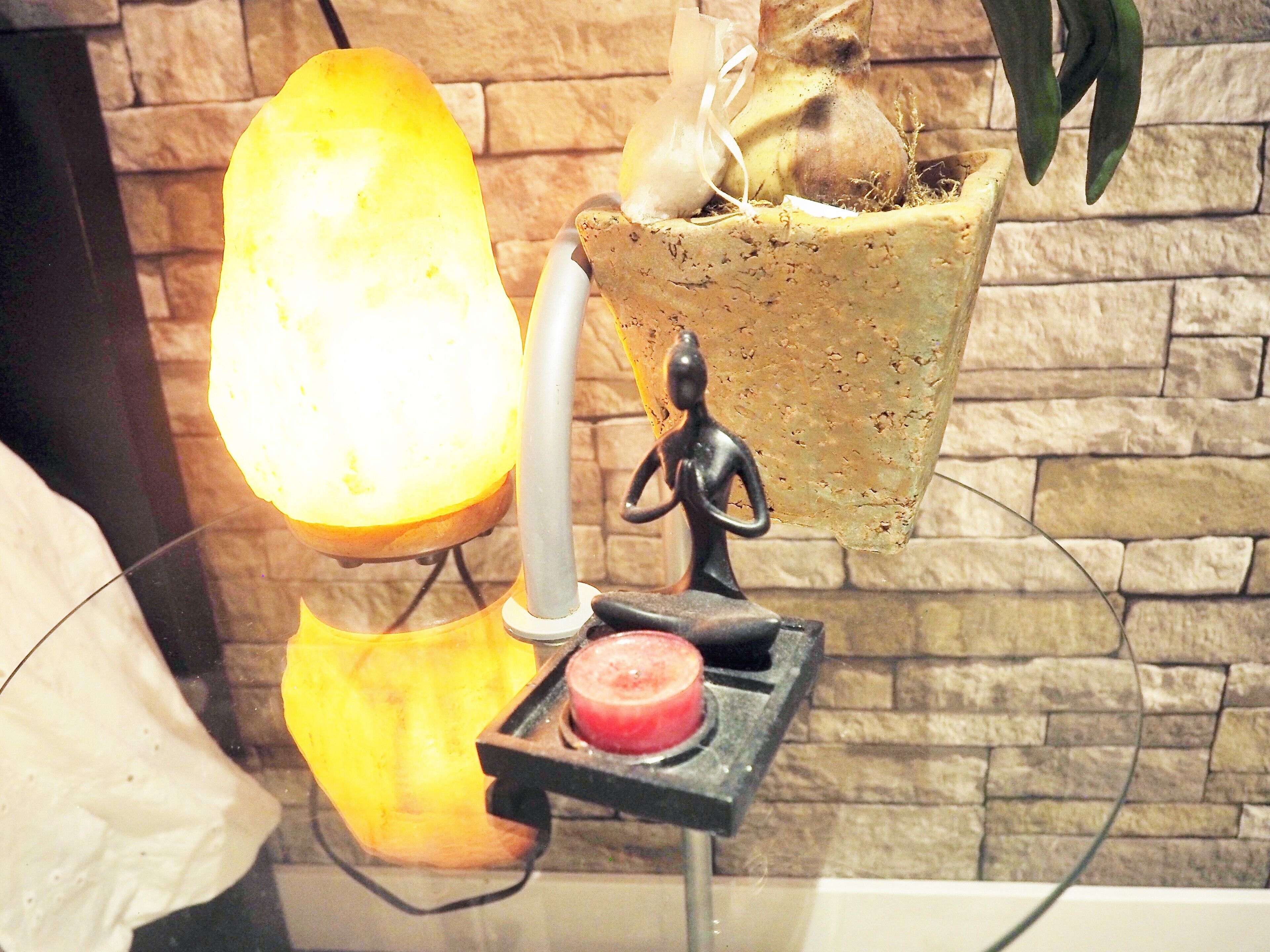 Une lampe murale avec un abat-jour jaune, une petite figurine et un objet rouge posé sur un support.