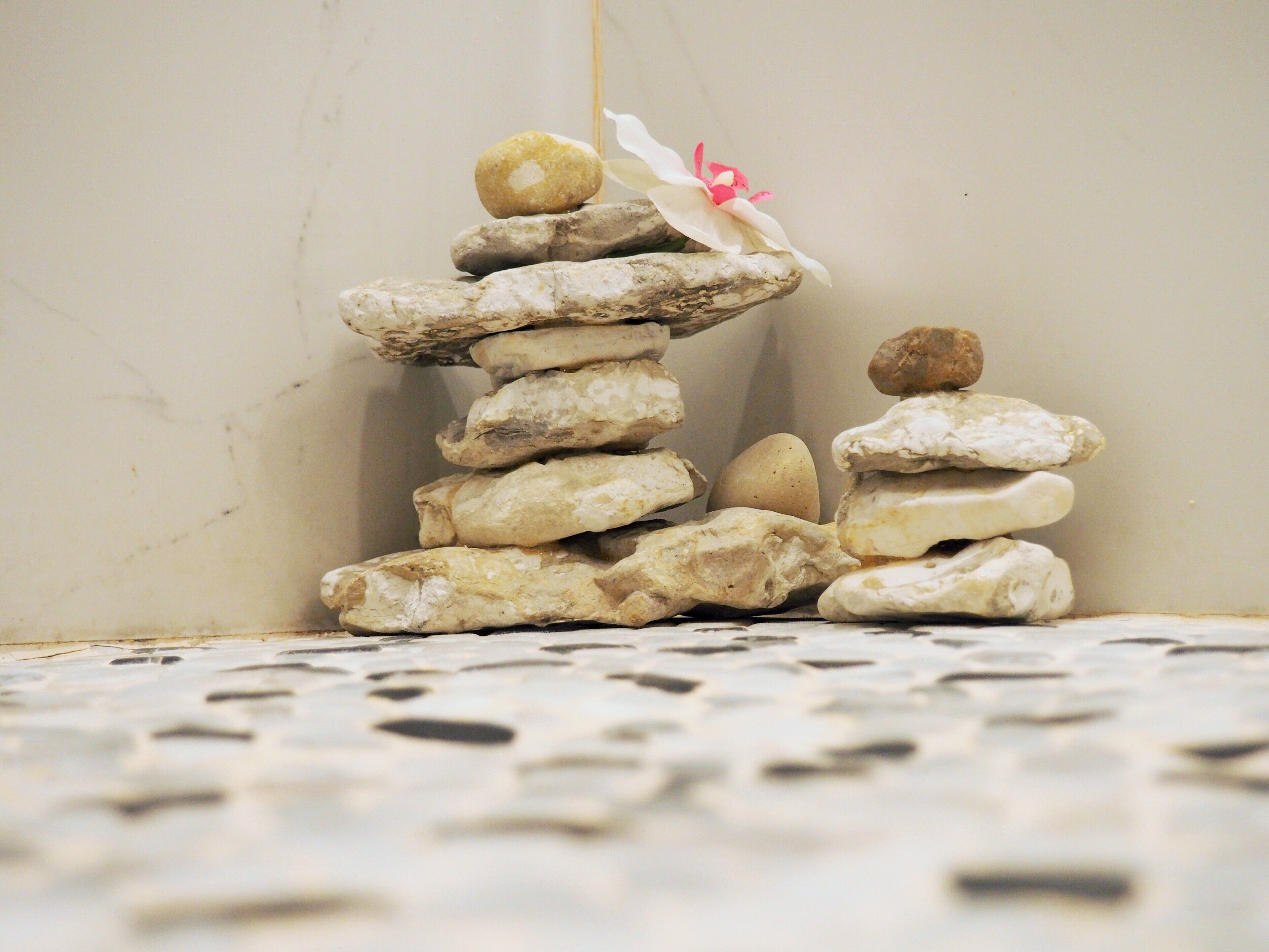 A stack of smooth, rounded stones with a single flower on top.