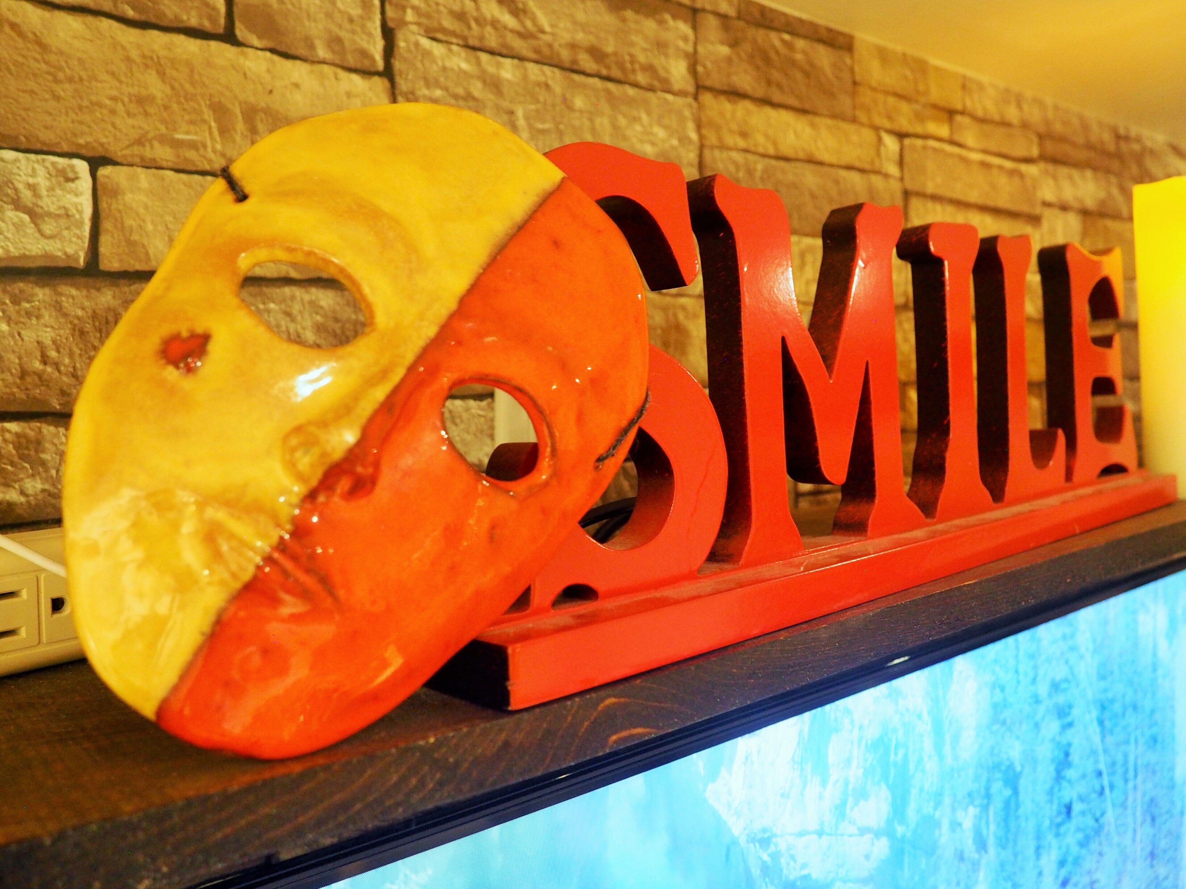 Un masque et des lettres formant le mot « SMILE » sur une étagère.