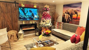 A living room with a fireplace, a television, a sofa, a coffee table, and a decorative floral arrangement.