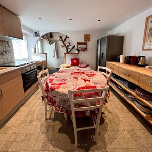 A compact kitchen with a dining area, equipped with a refrigerator, stove, and various kitchen utensils.