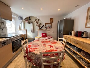 A compact kitchen with a dining area, a refrigerator, and a microwave. - Homerez - Apartment Gérardmer (Gérardmer)