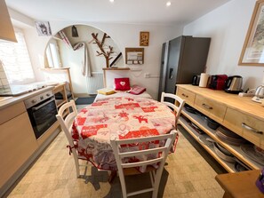 A compact kitchen with a dining area, a refrigerator, and a microwave. - Homerez - Apartment Gérardmer (Gérardmer)