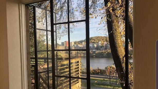 Une fenêtre donnant sur un lac, une terrasse en bois et, au loin, une vue sur la ville.