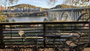 Une vue sur le fleuve, avec un pont, des tables à l’extérieur et des bâtiments en arrière-plan.