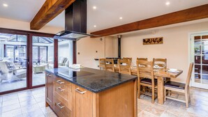 Una cocina con armarios de madera, encimera negra y comedor con sillas y mesa de madera.